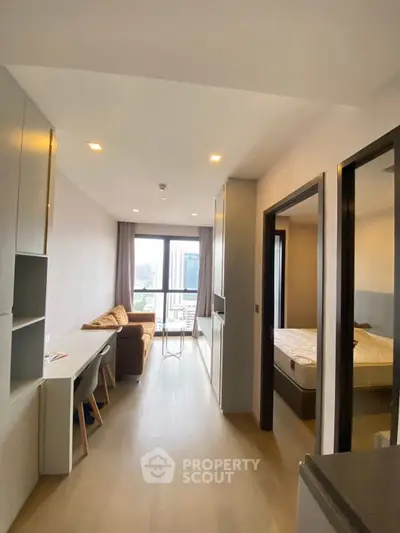 Modern apartment interior with open living room and bedroom, featuring large windows and stylish furniture.