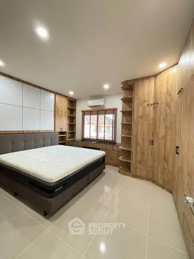 Spacious modern bedroom with built-in wooden storage and large window