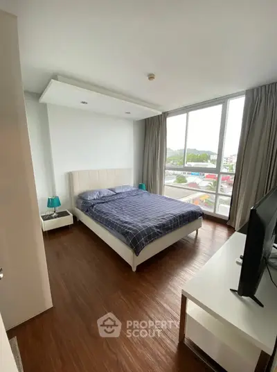 Modern bedroom with large windows and wooden flooring offering a bright and cozy atmosphere.