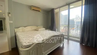 Spacious bedroom with elegant bed and city view balcony in modern apartment.