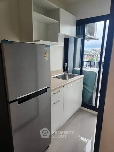 Modern kitchen with sleek fridge and balcony view in stylish apartment