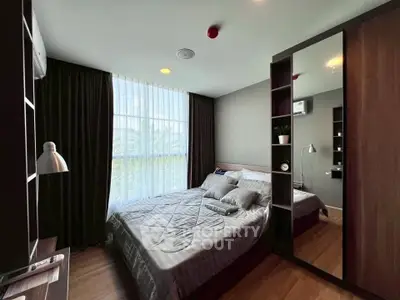 Modern bedroom with large window and stylish decor in a cozy apartment.