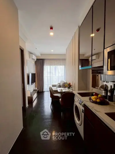 Modern apartment with open kitchen and cozy living area, featuring sleek appliances and stylish decor.