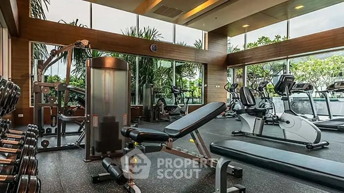 Luxurious gym with modern equipment and panoramic garden views in upscale residential building.