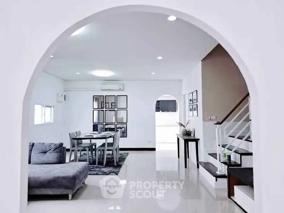 Elegant open-plan living and dining area with modern decor and staircase