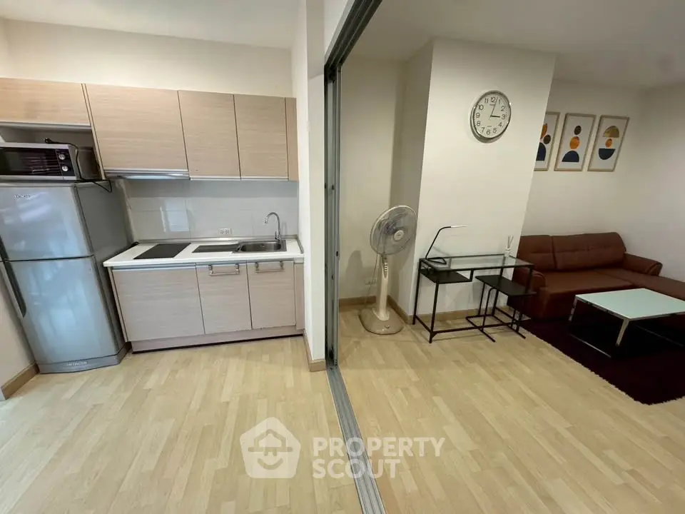 Modern apartment with open kitchen and cozy living area, featuring sleek appliances and stylish decor.
