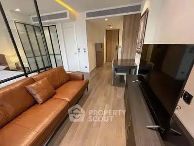 Modern living room with leather sofa and sleek TV setup in stylish apartment.