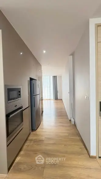 Modern kitchen with sleek appliances and wooden flooring in a bright apartment.