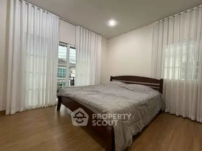 Spacious bedroom with wooden flooring and large windows for natural light.