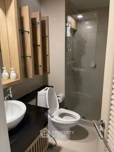 Modern bathroom with glass shower and stylish wooden shelving.