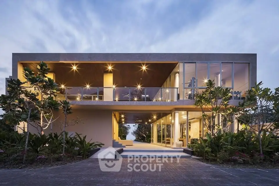 Stunning modern architectural home with expansive glass windows and lush landscaping.