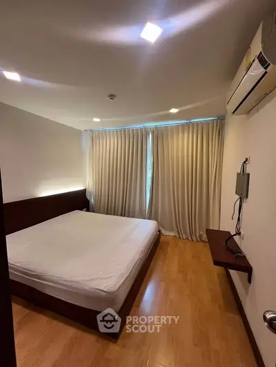 Spacious bedroom with modern design and natural light, featuring a large bed and wooden flooring.