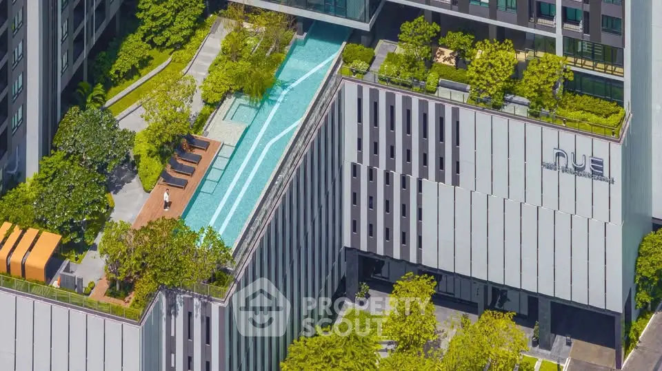 Modern building with rooftop pool and lush greenery in urban setting.