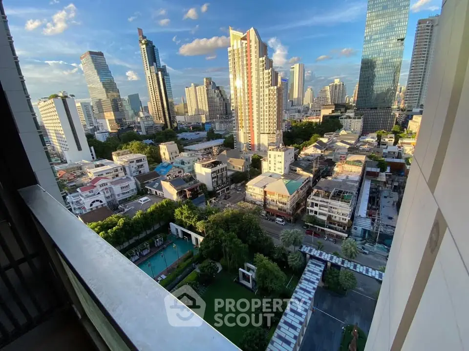 Stunning cityscape view from a high-rise balcony overlooking urban skyline and lush greenery.