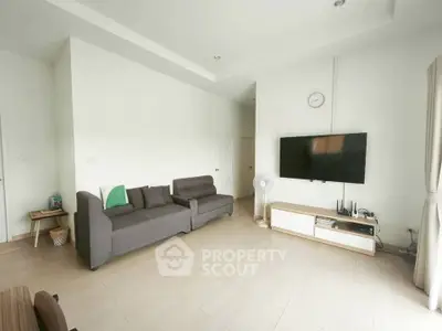 Spacious modern living room with sleek furniture and wall-mounted TV, perfect for relaxation and entertainment.
