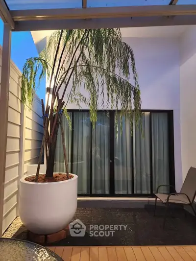 Charming balcony with potted plant and seating area, perfect for relaxation.
