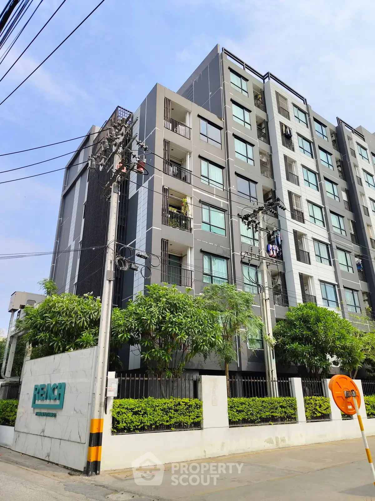 Modern condominium building with lush greenery and clear blue sky, ideal urban living.