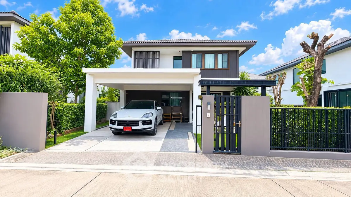 Modern two-story house with carport and landscaped garden in a serene neighborhood.
