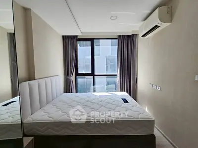 Modern bedroom with large window and air conditioning unit, featuring a comfortable mattress.