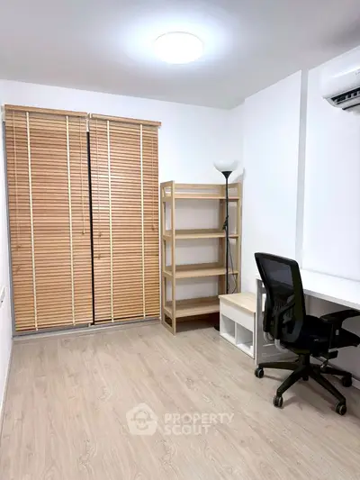 Minimalist study room with wooden flooring, desk, chair, and shelving unit.
