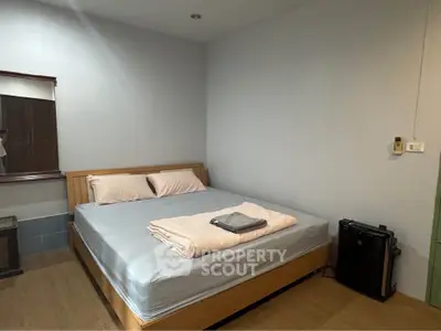Cozy bedroom with wooden flooring and neatly arranged bed in a minimalist style.