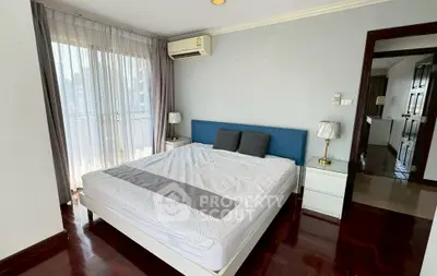 Spacious bedroom with large windows and city view, featuring modern decor and air conditioning.