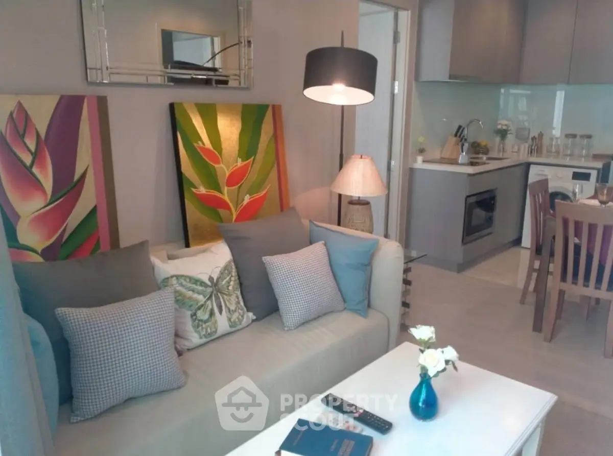 Chic living room with modern kitchen, vibrant artwork, and cozy seating in open layout apartment.