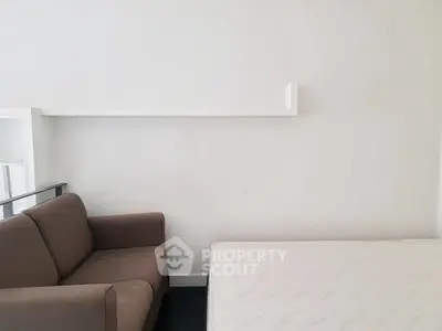 Minimalist bedroom with brown sofa and white mattress, ideal for cozy living.