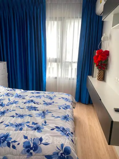 Cozy bedroom with floral bedding and vibrant blue curtains, perfect for a restful retreat.
