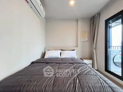 Cozy bedroom with modern decor and large window for natural light.