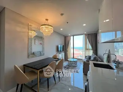 Luxurious modern living room with ocean view, elegant chandelier, and open kitchen layout.