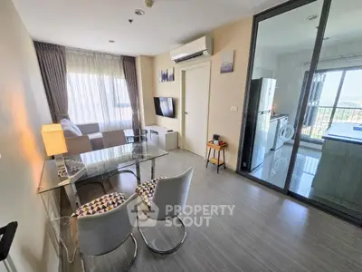 Modern living room with glass dining table and view into kitchen with appliances
