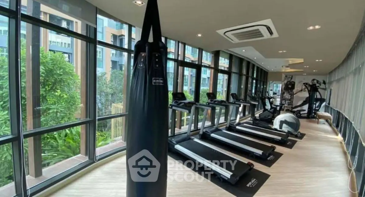 Modern gym with treadmills and punching bag in luxury apartment complex.