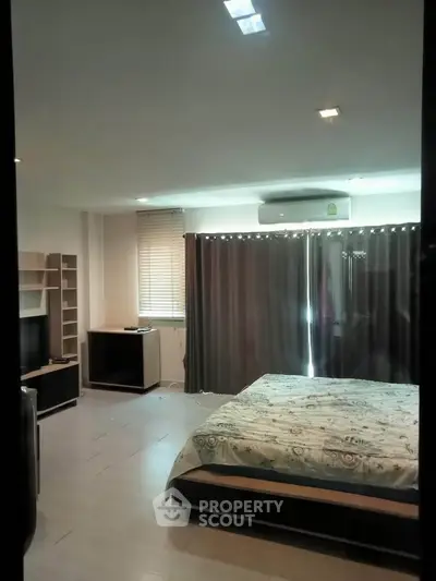 Spacious bedroom with modern decor and large window for natural light.