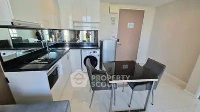 Modern kitchen with sleek appliances and dining area in compact apartment.