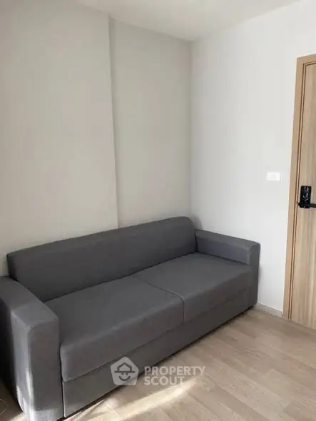 Modern minimalist living room with sleek gray sofa and wooden flooring.