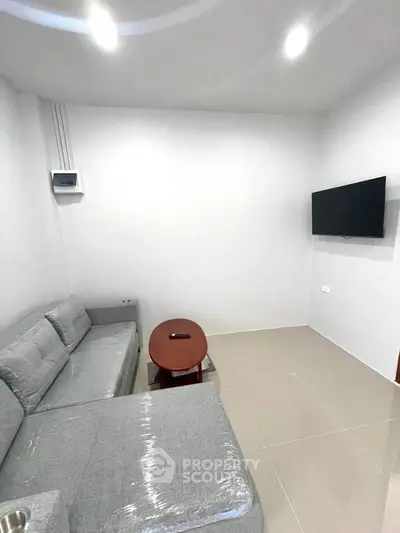 Modern minimalist living room with sleek gray sofa and wall-mounted TV, perfect for cozy relaxation.