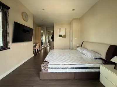 Spacious modern bedroom with stylish decor and large TV