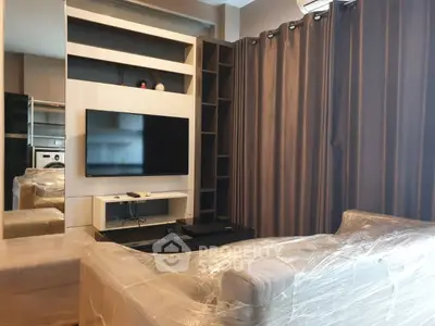 Modern living room with TV and stylish furniture, wrapped for protection.