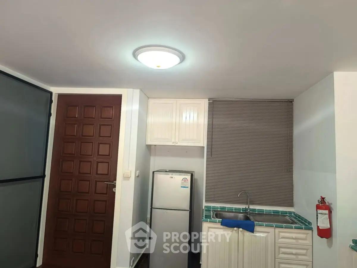 Compact kitchen with fridge and tiled countertop in cozy apartment