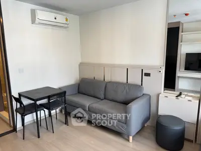 Modern living room with gray sofa, dining table, and air conditioning in a stylish apartment.