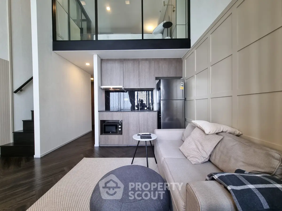 Modern loft apartment with sleek kitchen and cozy living area, featuring high ceilings and stylish decor.