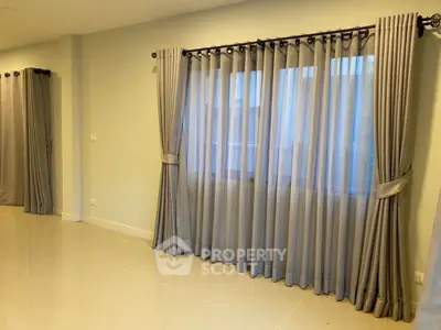 Spacious room with elegant curtains and polished tile flooring, ideal for modern living.