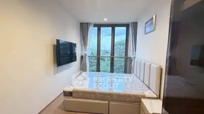 Modern bedroom with large window and wall-mounted TV, offering a serene view.