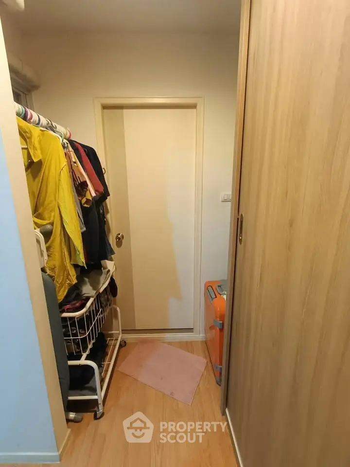 Compact storage room with wooden flooring and closet space
