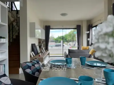 Stylish living room with modern decor and dining area, featuring large windows and natural light.