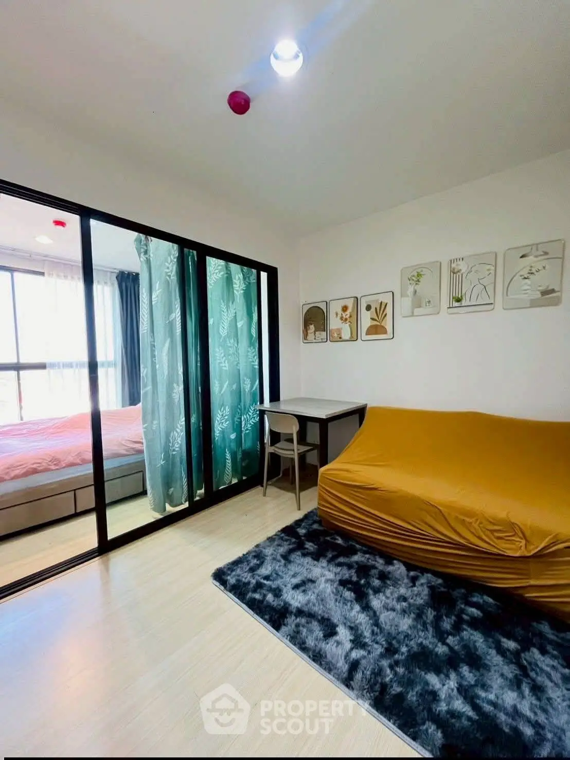 Modern apartment with cozy living area and stylish bedroom separated by glass doors.