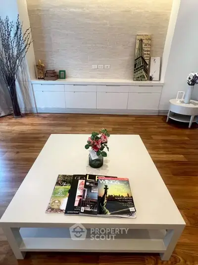 Stylish living room with modern decor and wooden flooring, featuring a chic coffee table and elegant wall unit.