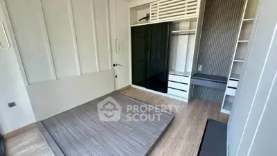 Modern bedroom with sleek built-in wardrobe and minimalist design, featuring light wood flooring and neutral tones.