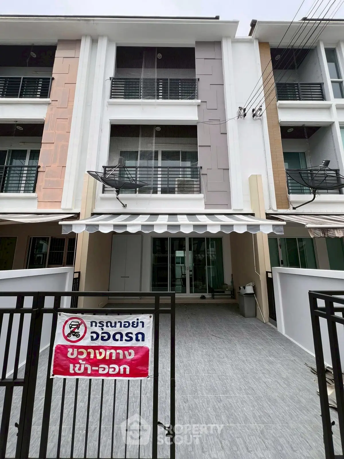 Modern townhouse exterior with gated entrance and balcony in urban setting.